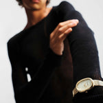 JONES + CO Jane Tethered watch with gold oval case, champagne mother-of-pearl dial, and woven mesh bracelet on wrist