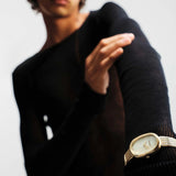 JONES + CO Jane Tethered watch with gold oval case, champagne mother-of-pearl dial, and woven mesh bracelet on wrist