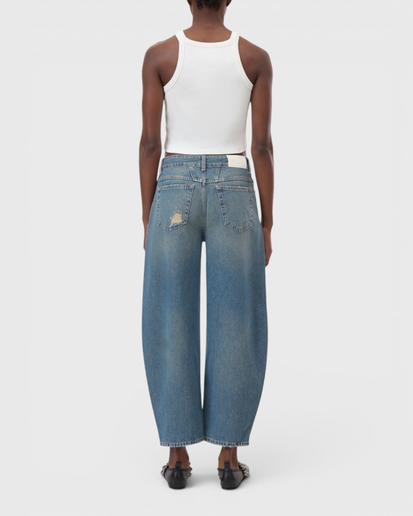 JONES + CO Jazzie barrel jeans in distressed blue denim with a mid-waist, cropped leg, and vintage patched holes.