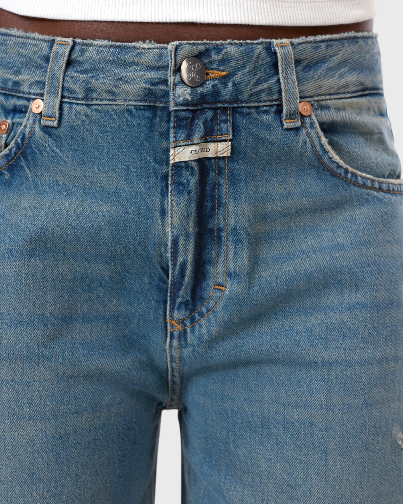 JONES + CO Jazzie barrel jeans in distressed blue denim with a mid-waist cut, five pockets, and vintage wash.