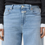 JONES + CO Jazzie barrel jeans in light blue denim with a mid-rise waist, five-pocket design, and button-zip closure.