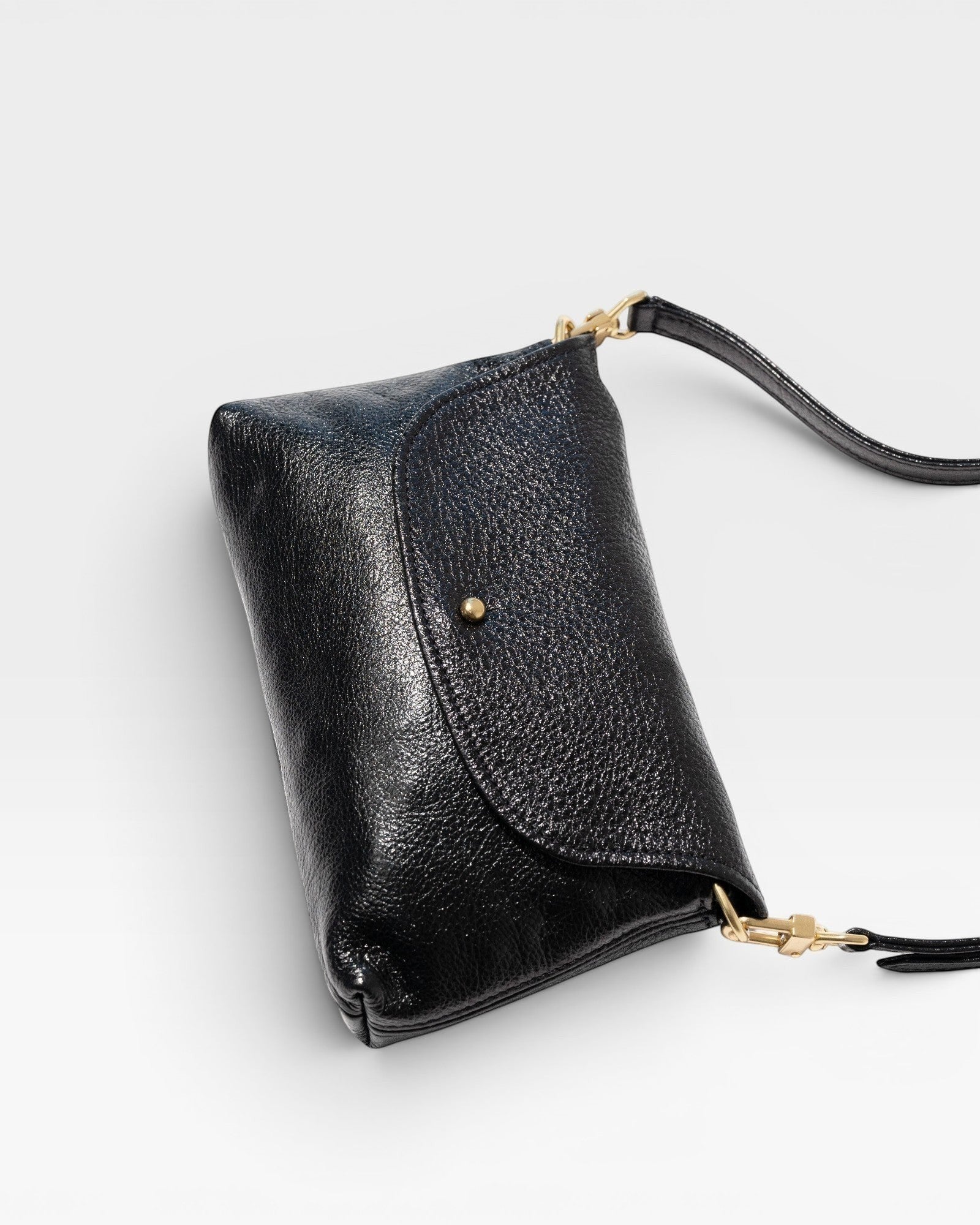 JONES + CO Kaanapali Crossbody in black metallic aniline leather with brass hardware and collar button closure.
