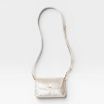 JONES + CO Kaanapali crossbody bag in champagne metallic aniline leather with a flap closure and adjustable strap.