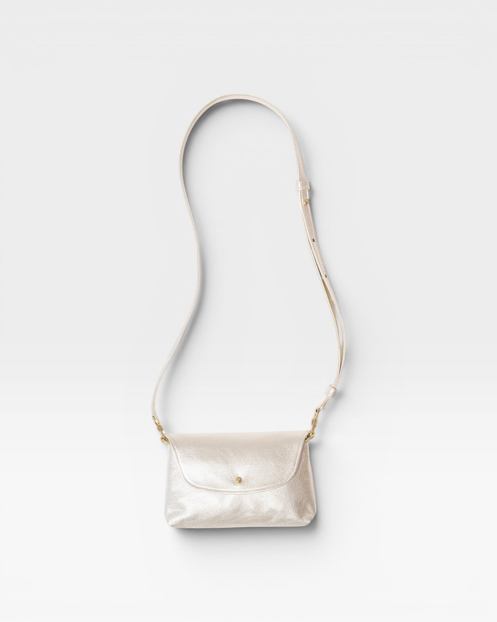 JONES + CO Kaanapali crossbody bag in champagne metallic aniline leather with a flap closure and adjustable strap.
