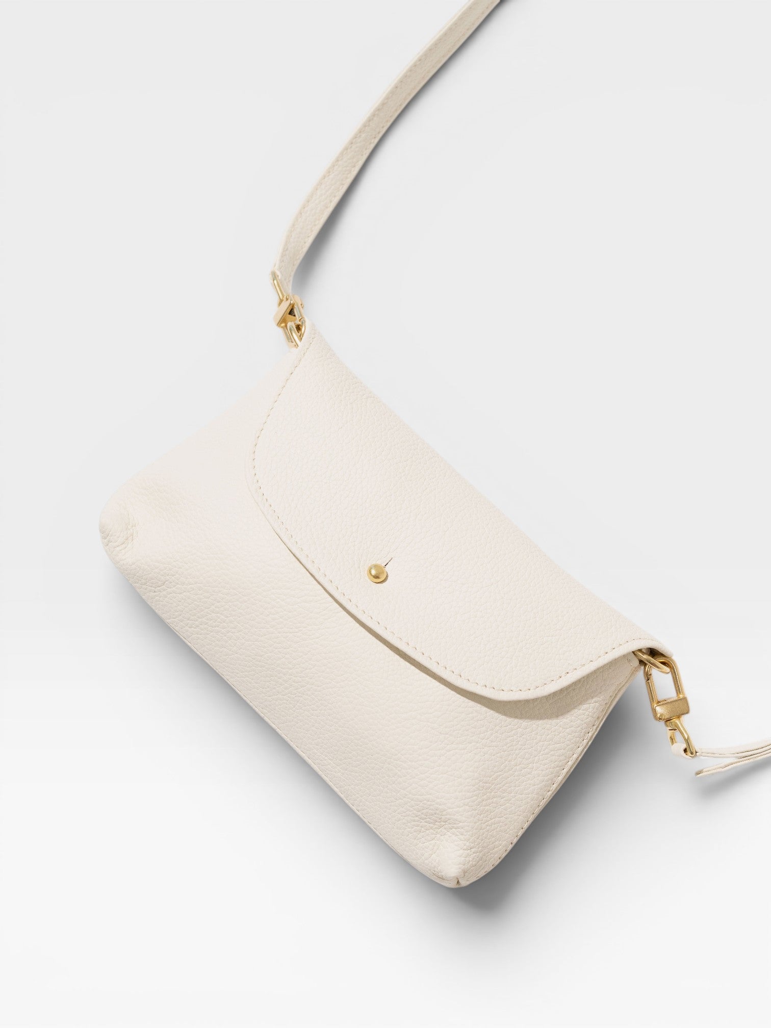 JONES + CO Kaanapali Crossbody in milk pebble leather with gold hardware. Versatile for day or night.
