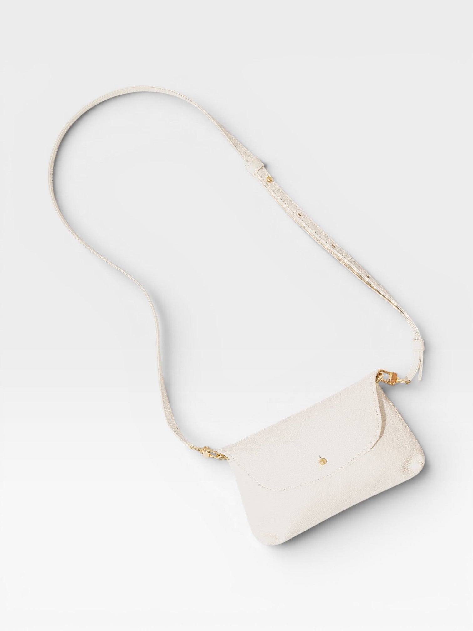 JONES + CO Kaanapali crossbody bag in milk pebble leather with gold hardware and adjustable strap.