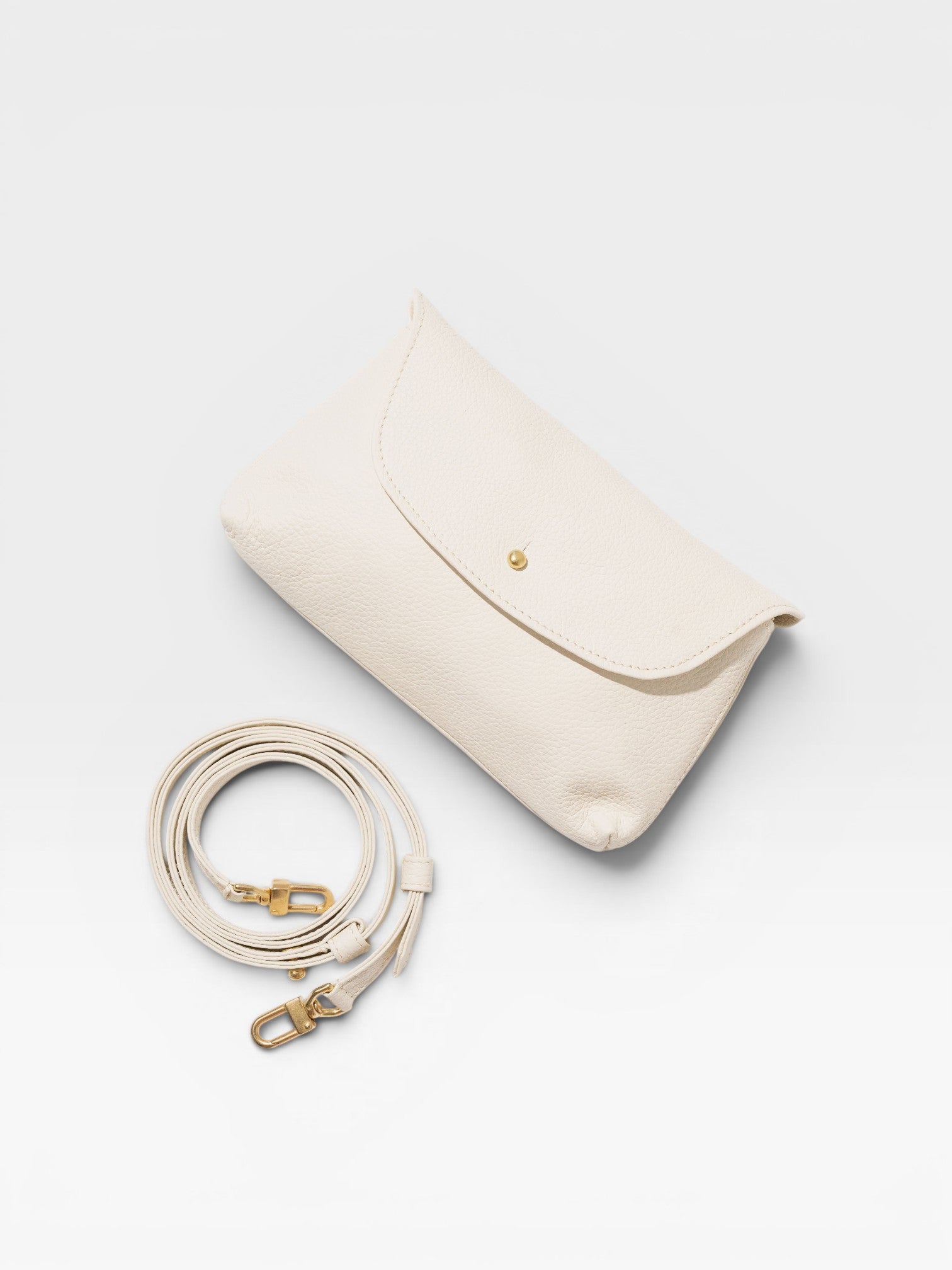 JONES + CO Kaanapali Crossbody in milk pebble leather with gold hardware and detachable strap.