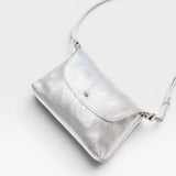 JONES + CO Kaanapali Crossbody in silver metallic aniline leather. Features a flap closure and adjustable strap.