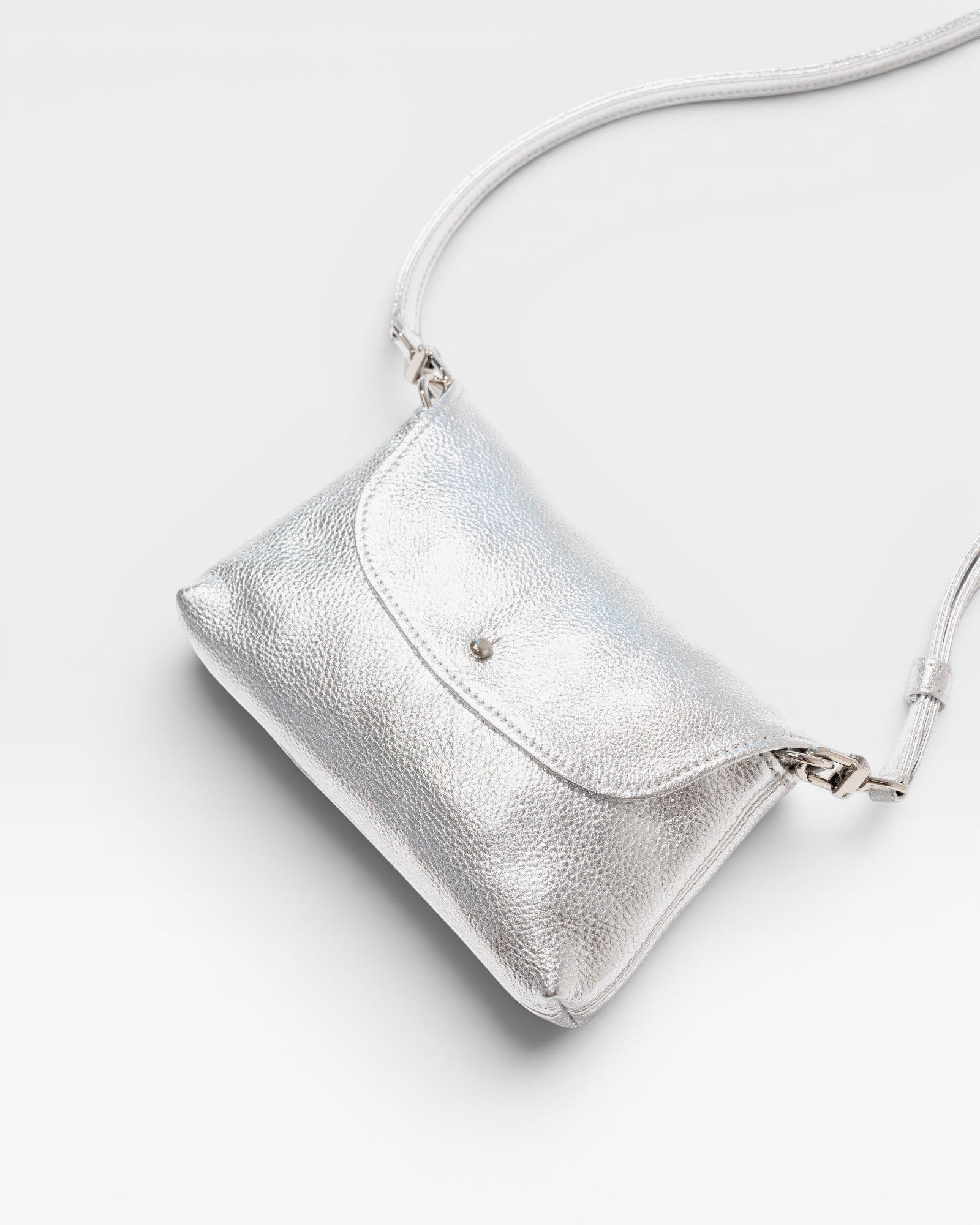 JONES + CO Kaanapali Crossbody in silver metallic aniline leather. Features a flap closure and adjustable strap.
