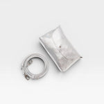 JONES + CO Kaanapali Crossbody in silver metallic aniline leather with detachable strap. Envelope flap closure.