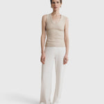 Model wearing a JONES + CO Kana Tank in dune beige, featuring a deep scoop neckline and ribbed knit fabric.