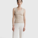 Model wearing a JONES + CO Kana Tank in dune beige with a deep scoop neckline and finely ribbed knit texture.