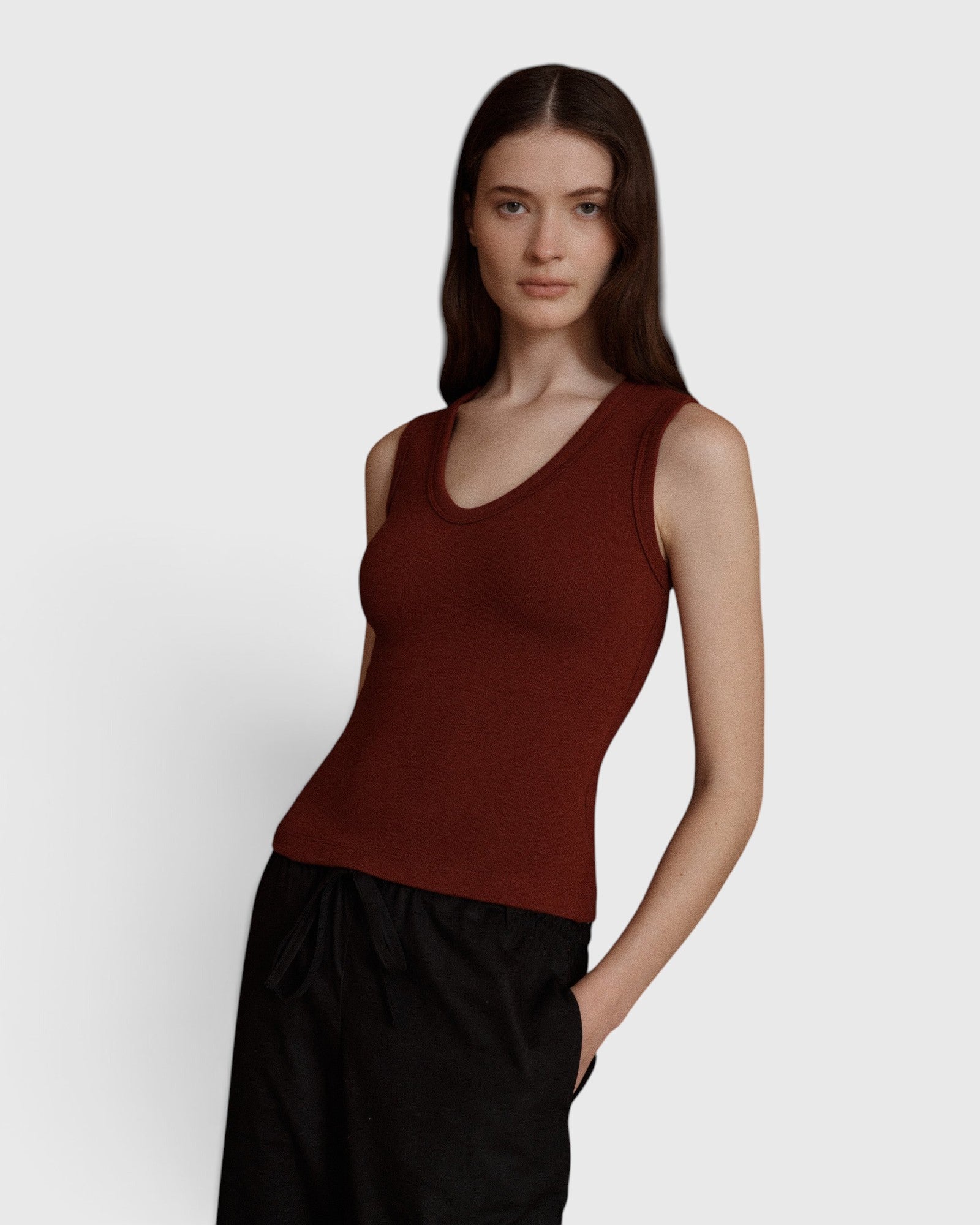 JONES + CO Kana Tank in merlot red, featuring a deep scoop neckline and finely ribbed knit fabric on a model.