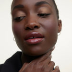 JONES + CO La Laque Tinted Lip Oil in a berry shade, providing sheer luminous color and a glossy finish.