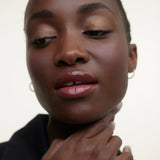 JONES + CO La Laque Tinted Lip Oil in a berry shade, providing sheer luminous color and a glossy finish.
