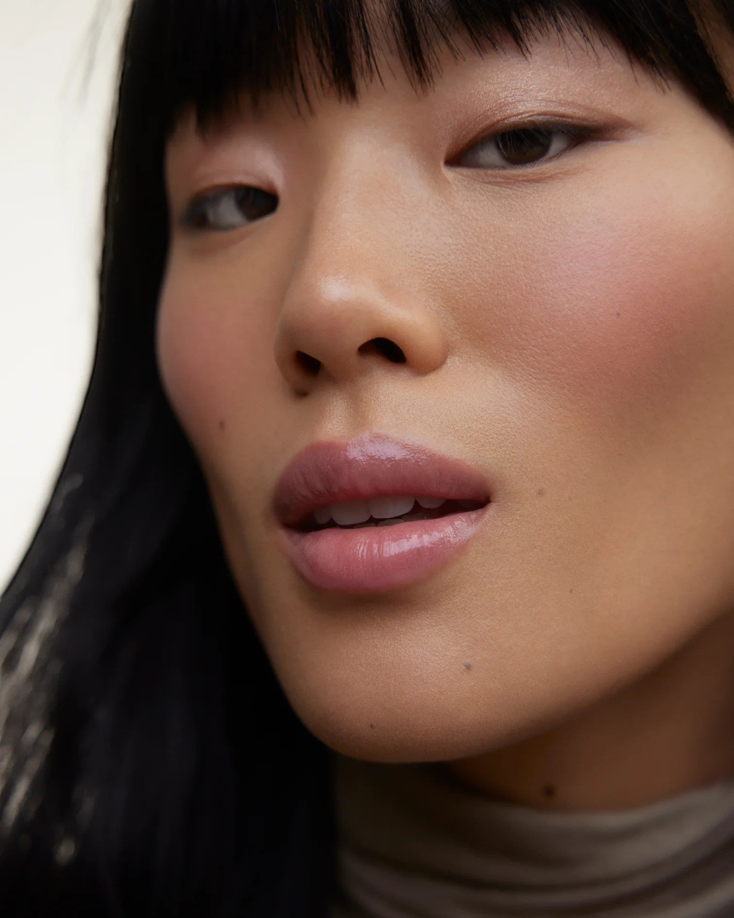 JONES + CO La Laque Tinted Lip Oil in a sheer rose shade, worn by a model with dark hair and subtle makeup.