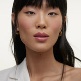 JONES + CO La Laque Tinted Lip Oil in a rosy pink shade, worn by a model with dark hair and fair skin.