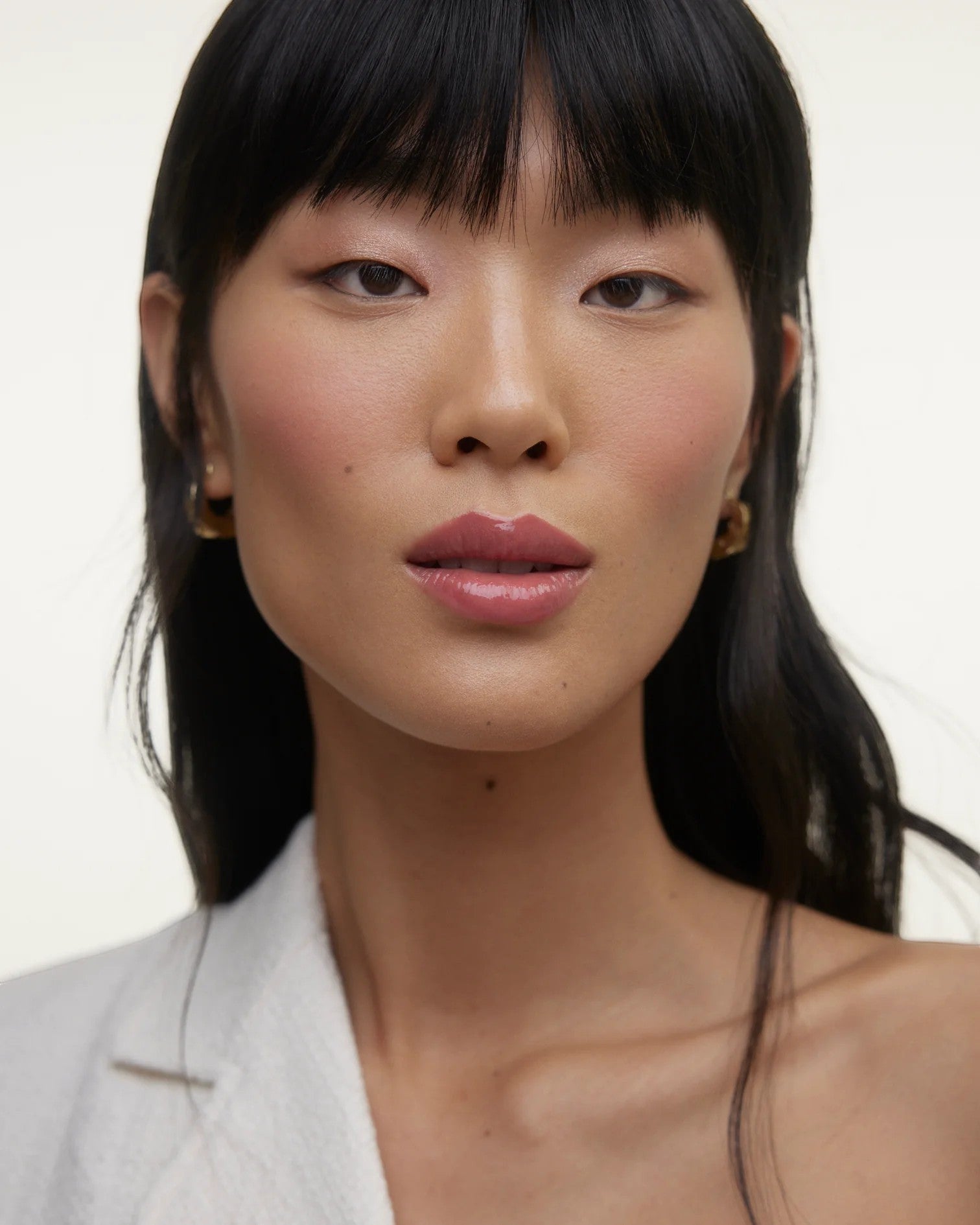 JONES + CO La Laque Tinted Lip Oil in a rosy pink shade, worn by a model with dark hair and fair skin.