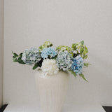 JONES + CO large ceramic vase with unique ash glaze, holding blue and green hydrangeas.