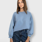 JONES + CO light blue crewneck sweatshirt with drop shoulders and raw edge hem worn by a woman