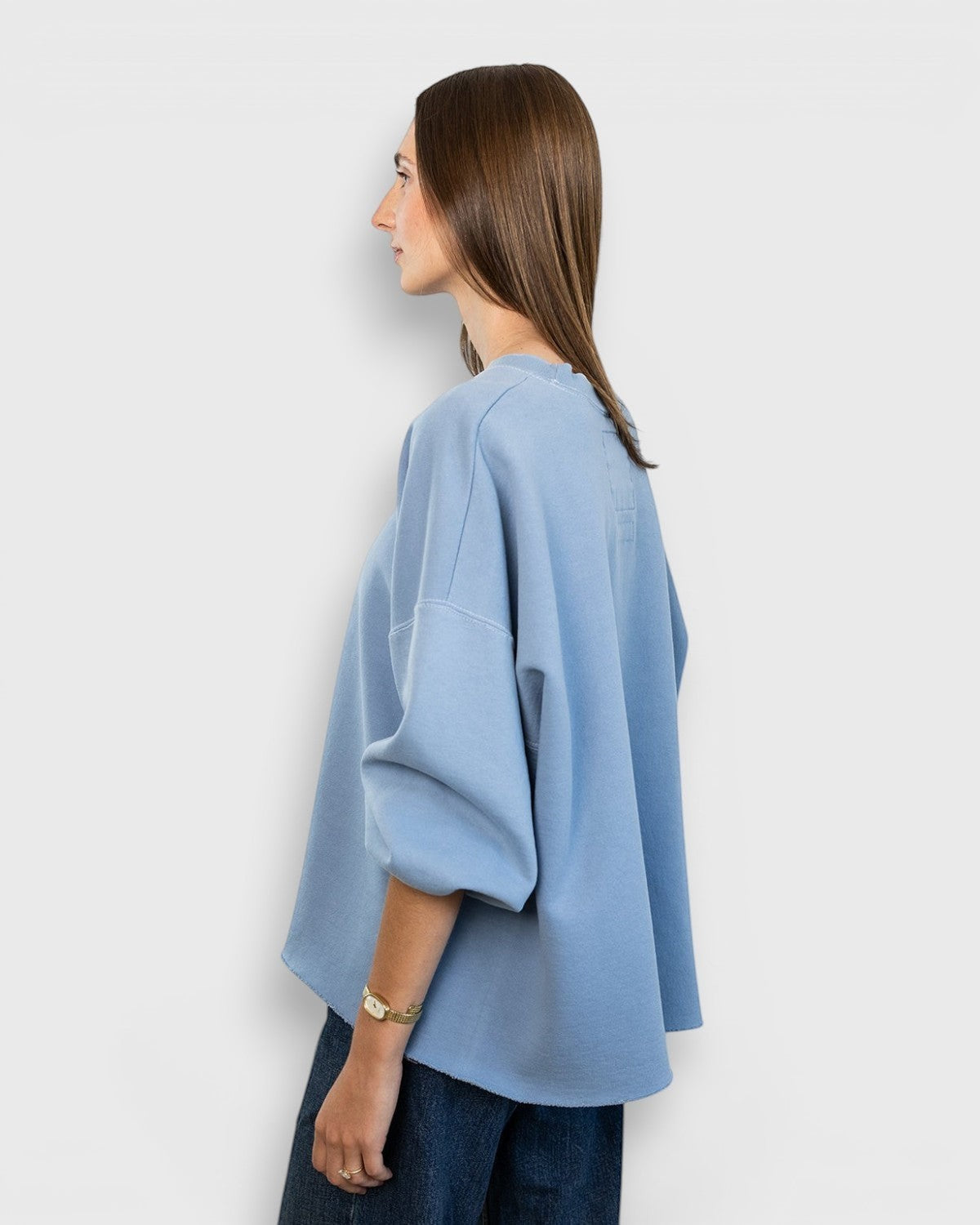 JONES + CO light blue Fond sweatshirt with drop shoulders and raw edge hem worn by a model in profile view