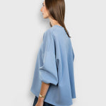 JONES + CO light blue Fond sweatshirt with drop shoulders and raw edge hem worn by a model in profile view