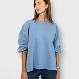 JONES + CO light blue crewneck sweatshirt with drop shoulders, cropped sleeves, and raw edge hemline on a model.