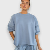 JONES + CO light blue crewneck sweatshirt with drop shoulders, cropped sleeves, and a raw edge hemline on a model.