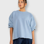 JONES + CO light blue crewneck sweatshirt with drop shoulders, cropped sleeves, and a raw edge hemline.