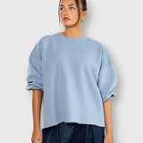 JONES + CO light blue crewneck sweatshirt with drop shoulders, cropped sleeves, and a raw edge hemline.