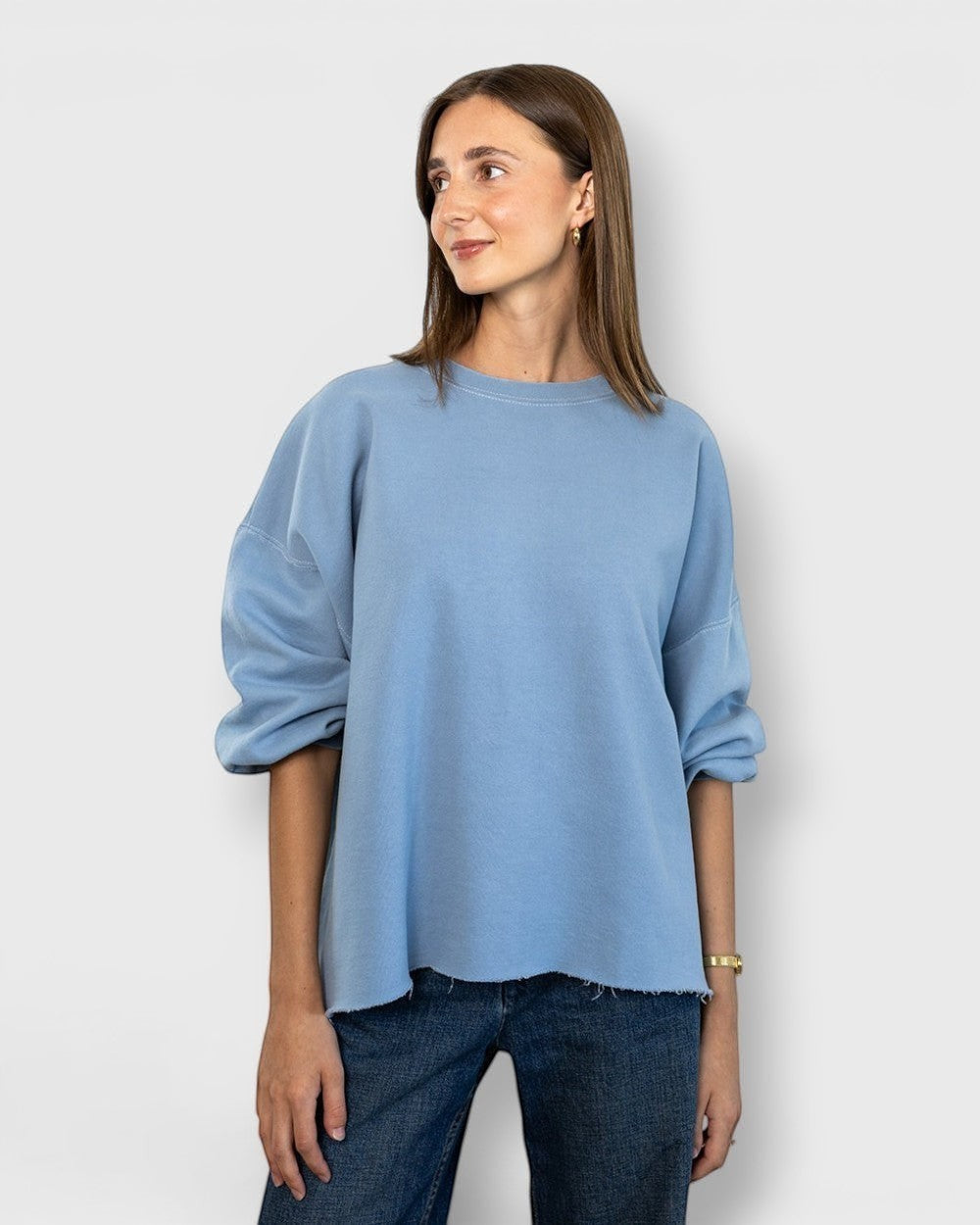 JONES + CO light blue crewneck sweatshirt with drop shoulders, cropped sleeves, and raw edge hemline on a model.