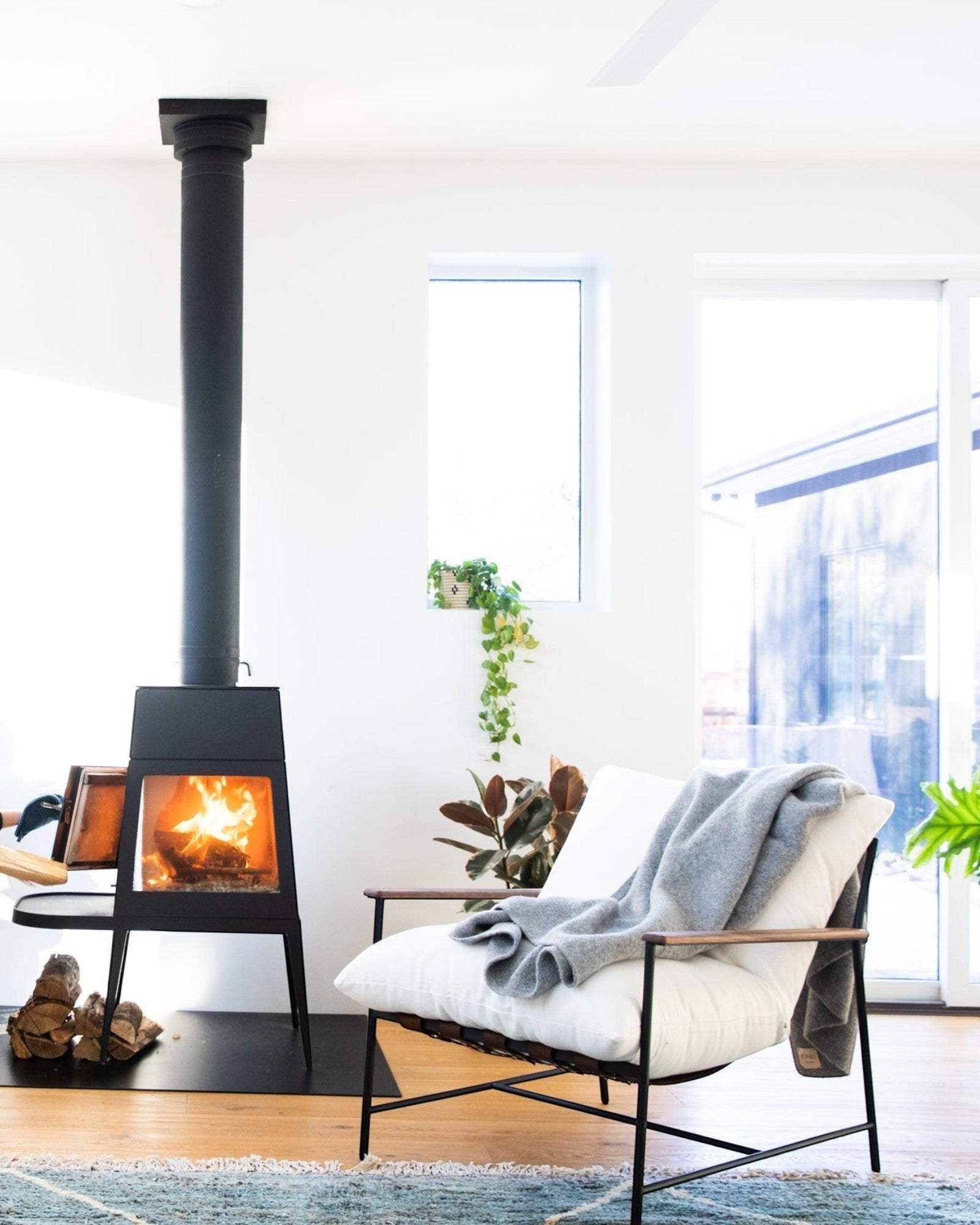 JONES + CO light grey alpaca wool blend throw blanket draped over a white armchair next to a fireplace.