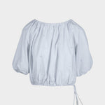 JONES + CO Lotus cropped blouse in light blue with short puff sleeves, drawstring waist, and French knot embroidery.
