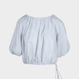 JONES + CO Lotus cropped blouse in light blue with short puff sleeves, drawstring waist, and French knot embroidery.