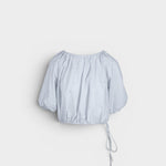 JONES + CO light blue cropped Lotus top with short sleeves, gathered cuffs, and drawstring waist, featuring French knot embroidery.