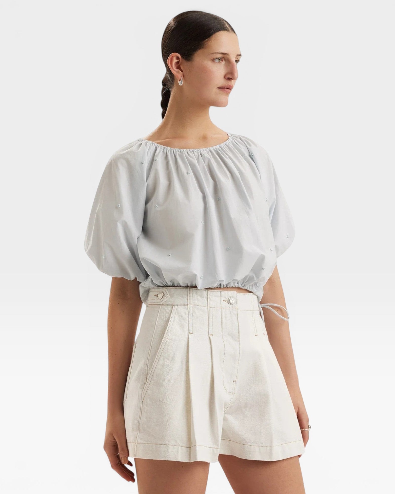 JONES + CO light blue cropped Lotus top with short sleeves, gathered cuffs, and French knot embroidery. Drawstring waist.