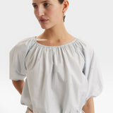 JONES + CO light blue cropped Lotus top with short sleeves, gathered cuffs, and French knot embroidery. Drawstring waist.