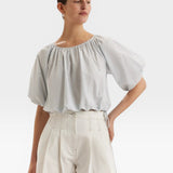 JONES + CO light blue cropped Lotus top with short sleeves, gathered cuffs, and French knot embroidery. Drawstring waist.