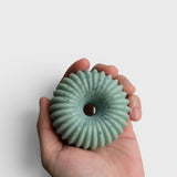 JONES + CO lülala bergamot and pink pepper soap bar in a pale green, ring-shaped design held in a hand.