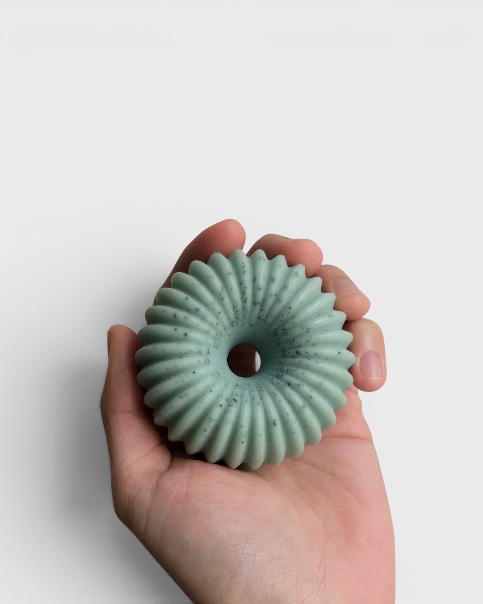 JONES + CO lülala bergamot and pink pepper soap bar in a pale green, ring-shaped design held in a hand.