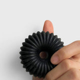 JONES + CO lülala black charcoal and sesame soap bar with a circular, fluted geometric design held in a hand.