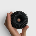 JONES + CO lülala black charcoal and sesame soap bar with a unique circular ribbed design held in a hand.