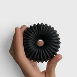 JONES + CO lülala black charcoal and sesame soap bar with a unique circular ribbed design held in a hand.