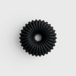JONES + CO lülala black charcoal and sesame soap bar with a circular, ribbed, geometric design.
