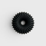 JONES + CO lülala black charcoal and sesame soap bar with a circular, ribbed, geometric design.