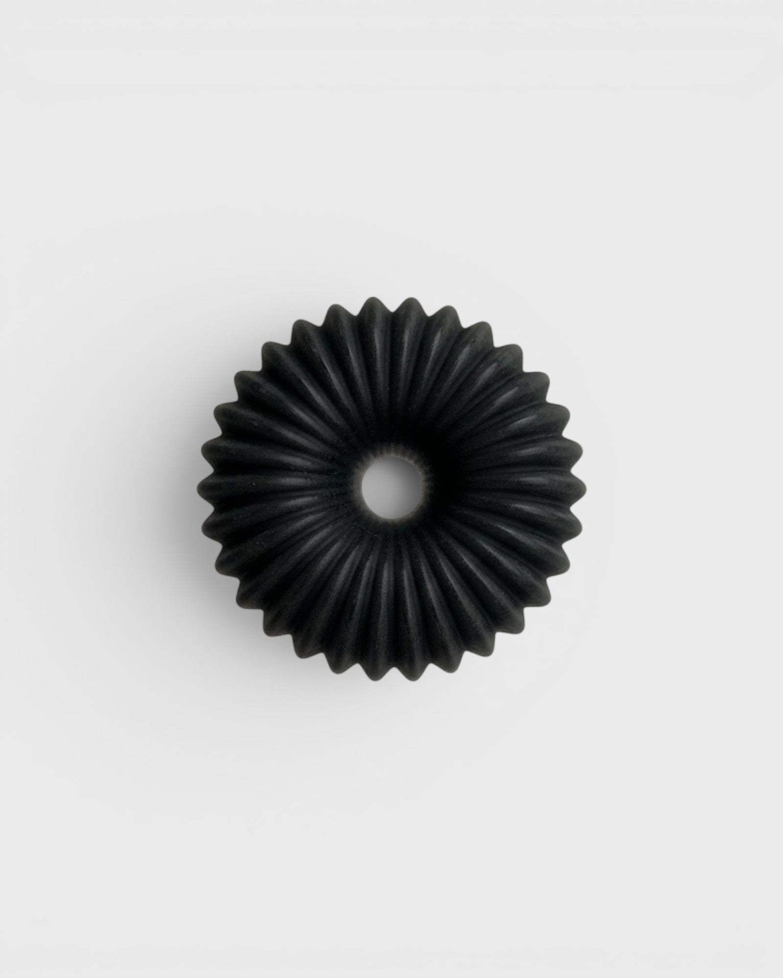 JONES + CO lülala black charcoal and sesame soap bar with a circular, ribbed, geometric design.
