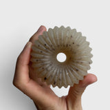JONES + CO lülala marjoram and sesame soap bar with a translucent, fluted, donut-like shape held in a hand.