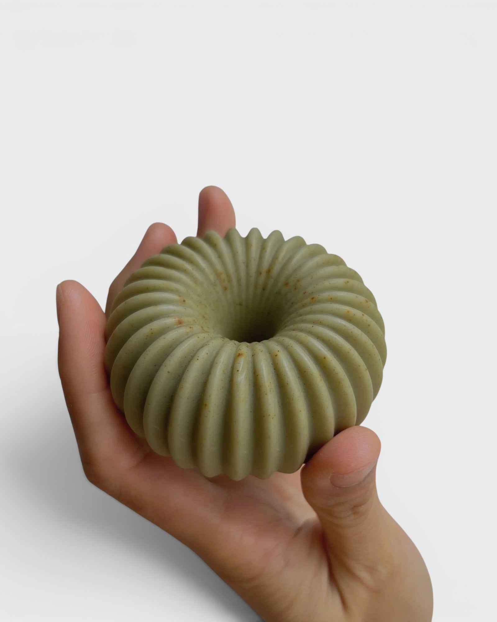 JONES + CO lülala hand-crafted soap bar in sage green with a ribbed, geometric donut shape held in a palm.