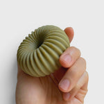 JONES + CO lülala hand-crafted soap bar in a sage green ribbed torus shape held in a hand