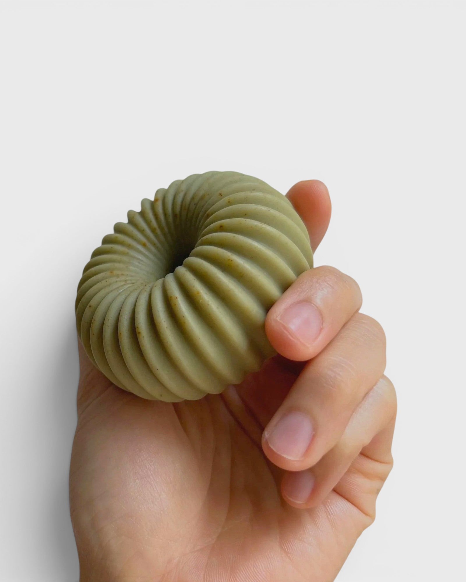 JONES + CO lülala hand-crafted soap bar in a sage green ribbed torus shape held in a hand
